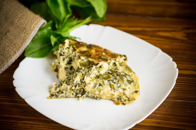 Tortilla de huevo frito con acedera de primavera en el interior sobre una mesa de madera