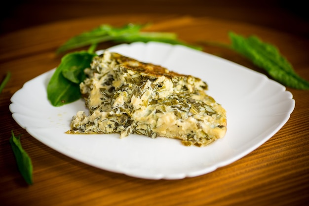 Tortilla de huevo frito con acedera de primavera en el interior sobre una mesa de madera