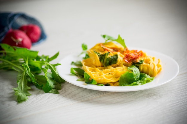 Tortilla de huevo rellena de tomate y verduras fritas en forma de gofres sobre una mesa de madera