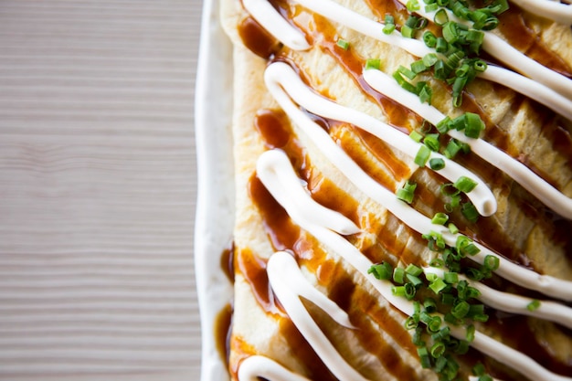 Tortilla japonesa rellena de verduras y con salsas por encima.