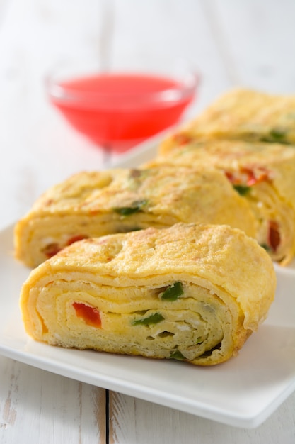 Tortilla japonesa de tamagoyaki tradicional en mesa de madera blanca.