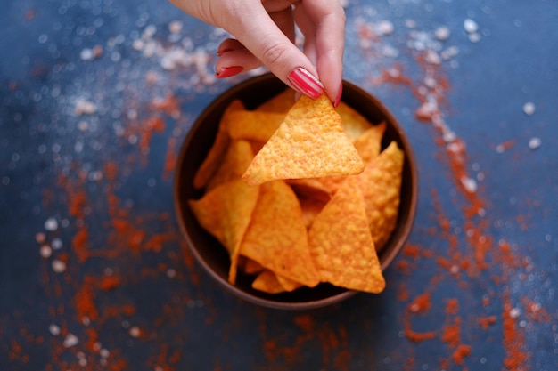 Tortilla nacho chips receta patatas fritas naturales en un tazón mano de mujer sosteniendo una rebanada triangular picante crujiente