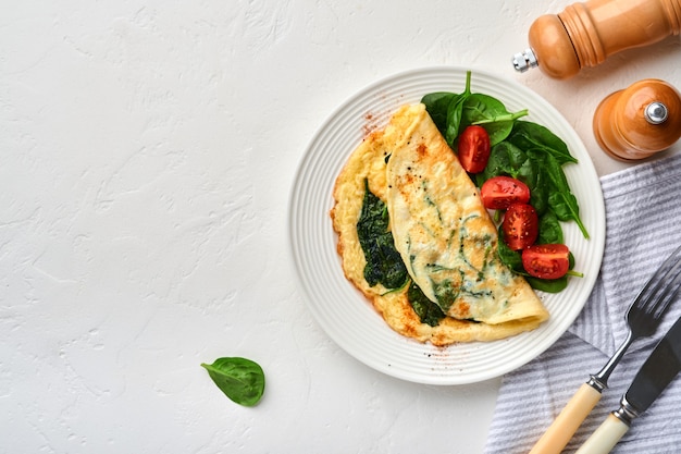 Tortilla o tortilla con espinacas, tomate cherry y condimento de pimiento en la placa blanca.