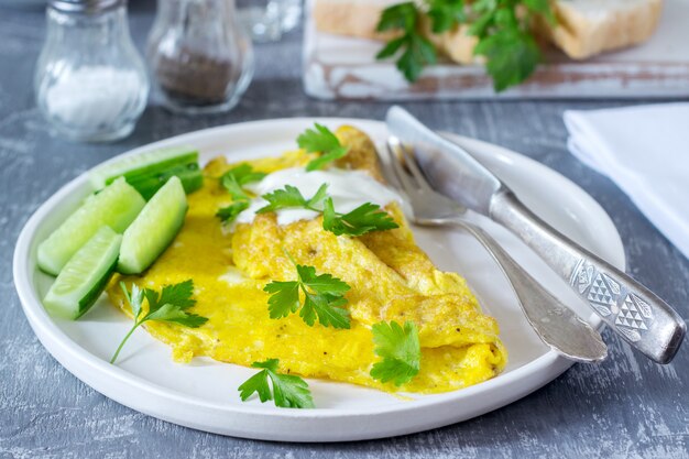 Tortilla con perejil, servida con crema agria y pepino fresco.