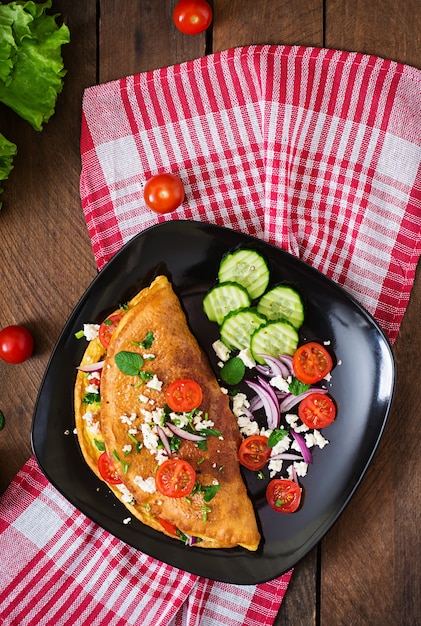 Tortilla con tomate, perejil y queso feta en placa negra. Vista superior