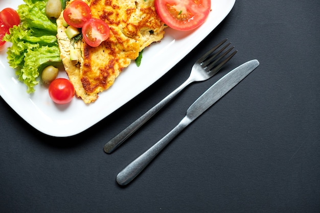 Tortilla de tomate servida con ensalada fresca. Fondo negro