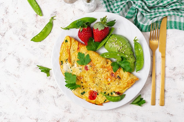 Tortilla con tomates, queso feta y aguacate en un plato blanco Vista superior endecha plana