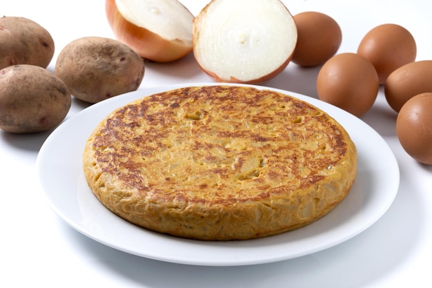 Tortilla tradicional española y ingredientes aislados sobre un fondo blanco