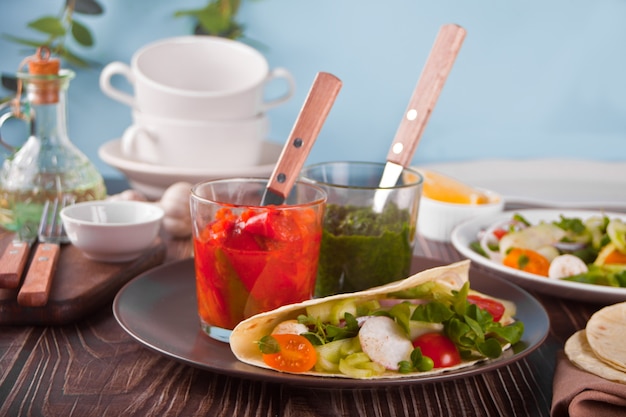 Tortilla vegana mexicana envuelva el pan plano con verduras y salsas en la mesa de la cena