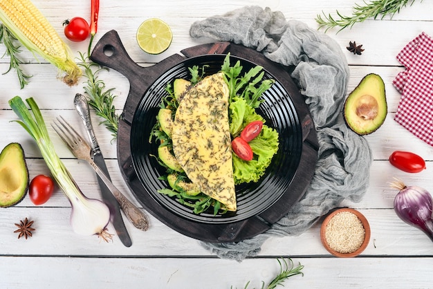 Tortilla con verduras y aguacates Huevos fritos Sobre un fondo de madera Vista superior Espacio de copia libre