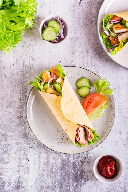 Tortilla-Wrap mit Gurke, Hähnchen und Tomate auf einem Teller Mexikanische Küche Ansicht von oben und vertikal