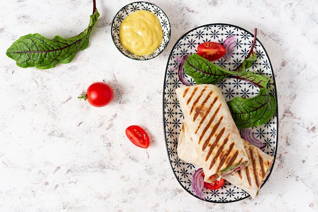 Tortilla-Wrap mit Schinken, Käse und Tomaten auf weißem Hintergrund Shawarma Draufsicht oben