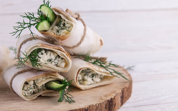 Tortilla-Wraps mit Hüttenkäse, Dill und Gurke auf Holzhintergrund.