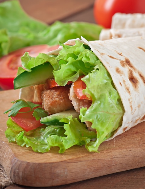 Tortillas frescas envueltas con nuggets de pollo y verduras en un plato