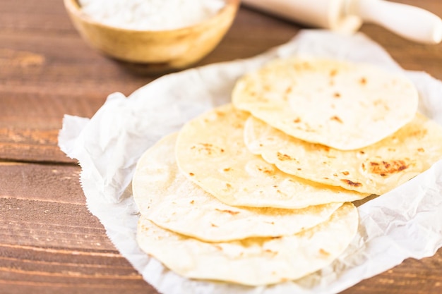 Tortillas de maíz blanco fresco sobre un papel blanco.