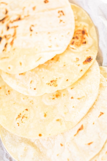 Tortillas de maíz blanco fresco sobre un papel blanco.