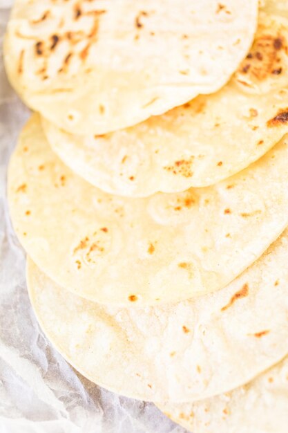 Tortillas de maíz blanco fresco sobre un papel blanco.