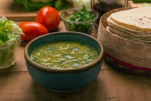 Tortillas Schüssel mit grüner Soße und Gemüse auf einem Holztisch Typisch mexikanisches Essen