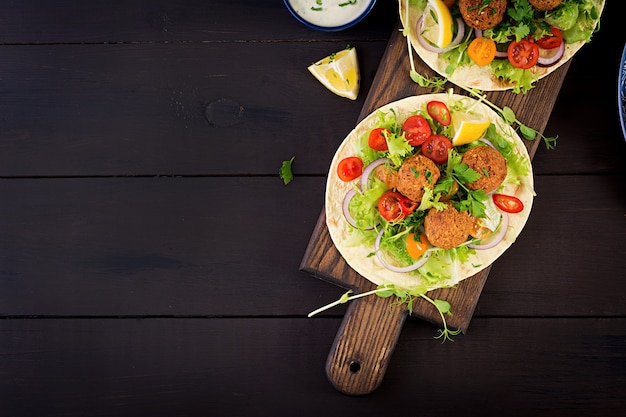 Tortillaverpackung mit Falafel und frischem Salat. Vegane Tacos. Vegetarisch gesundes Essen. Ansicht von oben