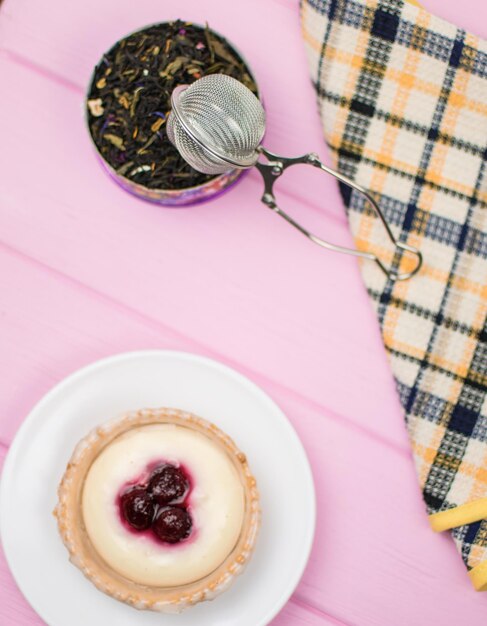 Tortinha com frutas e creme em um prato branco em um fundo rosa de madeira