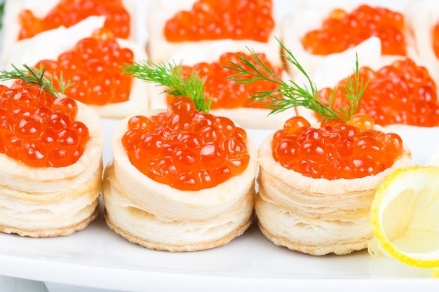 Tortinhas com caviar vermelho em um prato branco com limão