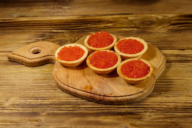 Tortinhas com caviar vermelho em uma mesa de madeira