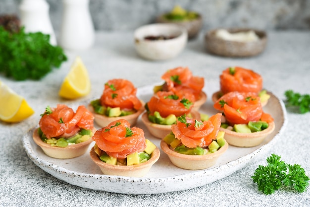 Tortinhas com cream cheese, abacate e salmão. aperitivo de salmão na mesa da cozinha.