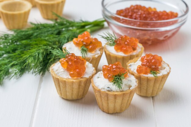 Tortinhas com cream cheese e caviar na parede de uma tigela de vidro com caviar vermelho. Aperitivo com delícias do mar.