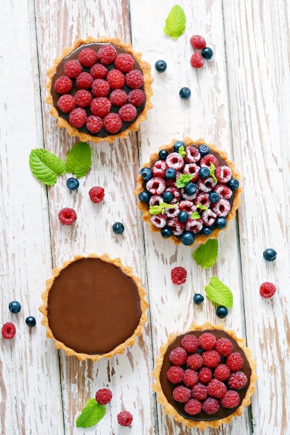 Tortinhas de framboesa e mirtilo com ganache de chocolate, frutas frescas e folhas de hortelã