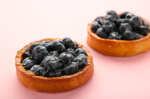 Tortinhas de mirtilo em fundo rosa Tortas caseiras com frutas pretas