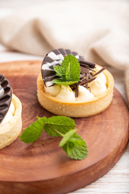 Tortinhas doces com creme de chocolate e queijo com café em um fundo branco de madeira e têxteis de linho. vista lateral, close-up, foco seletivo.