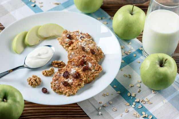 Tortitas de avena caseras con yogur vegano, pasas y nueces en la mesa de madera con tela azul en la caja.