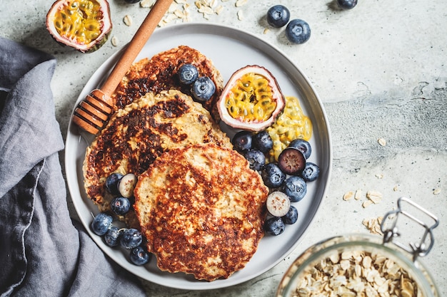 Tortitas de avena con miel, frutas y bayas, vista superior. Concepto de comida vegana saludable.