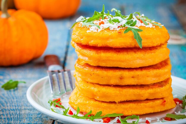 Tortitas de calabaza con chile, queso parmesano y rúcula closeup sobre fondo rústico