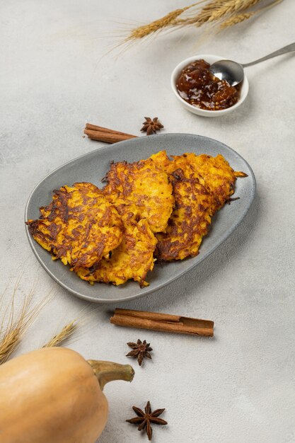 Tortitas de calabaza frescas en un plato sobre un fondo claro con calabaza y espiguillas de trigo