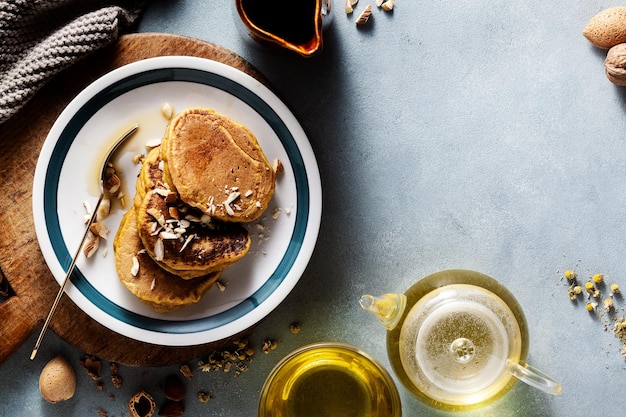 Tortitas de calabaza con nueces y jarabe de arce en una mesa con menú de otoño de té verde