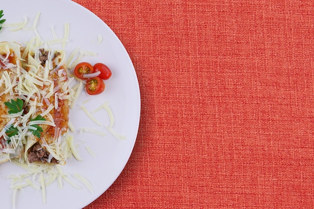 Tortitas con carne, en salsa de tomate y queso, con cilantro y queso rallado por encima.