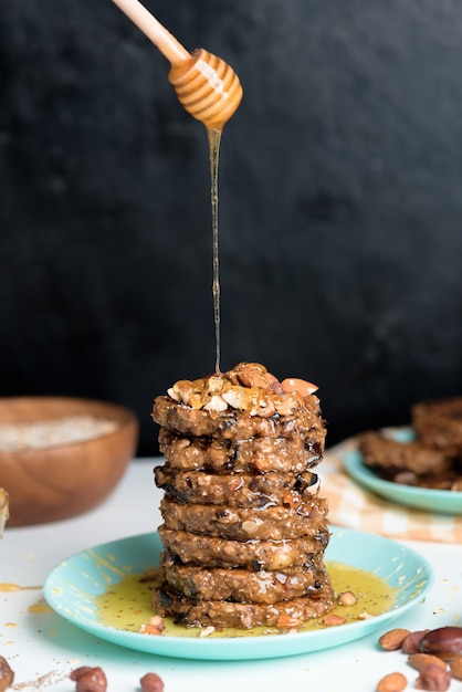 Tortitas caseras de avena y plátano con semillas de chía, almendras, ciruelas y dátiles, rociadas con miel y nueces trituradas