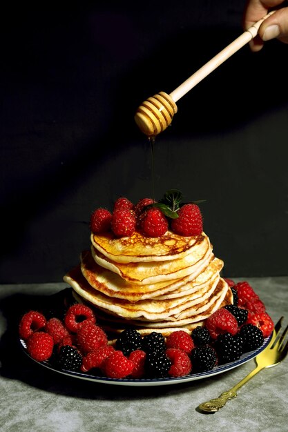 Tortitas caseras en un plato con frambuesas y moras. El concepto de una comida casera.