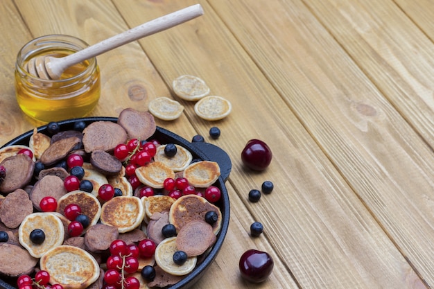 Tortitas de cereales y grosellas rojas, arándanos en sartén.