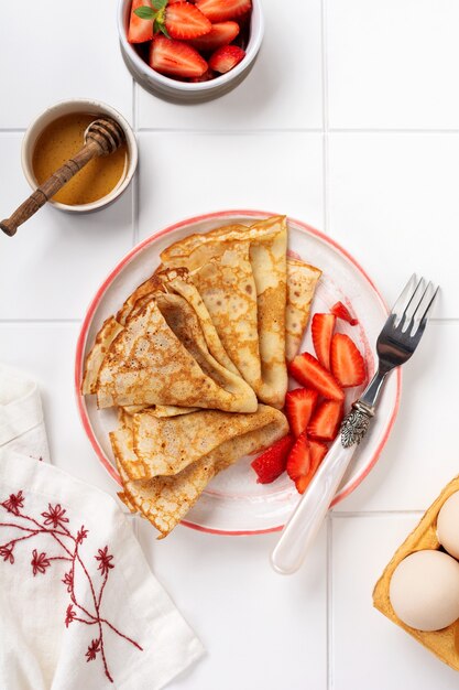 Tortitas de crepes con fresa fresca en plato de cerámica blanca. Vista superior.