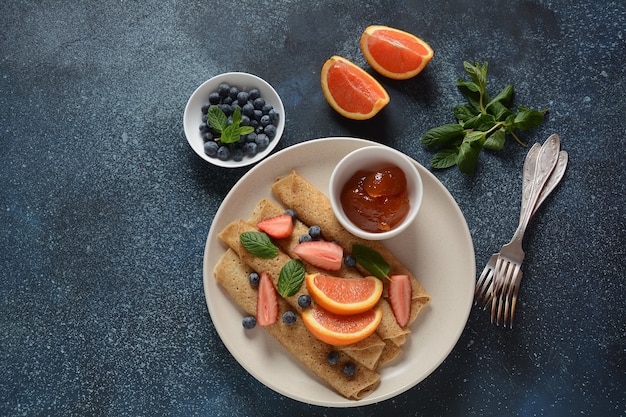 Tortitas dulces envueltas con menta fresca, fresas, arándanos, naranjas y mermelada