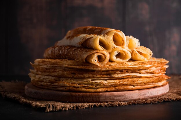 Tortitas finas de comida rusa tradicional Una pila de crepes sobre un fondo de madera marrón oscuro