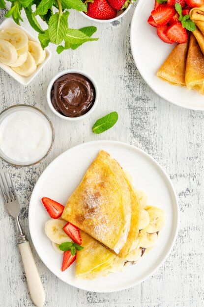 Foto tortitas finas o crepes con crema de chocolate y plátano