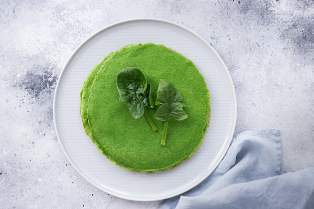 Foto tortitas finas verdes con espinacas sobre un fondo gris vista superior del concepto de comida vegana