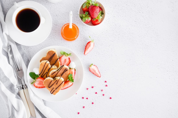 Tortitas en forma de corazón con salsa de chocolate y fresas frescas