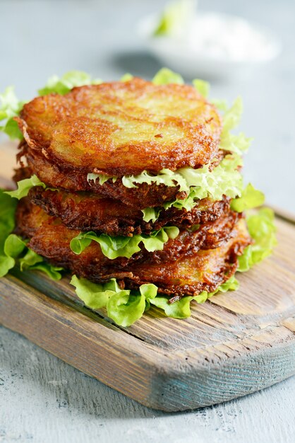 Tortitas de papa crujientes con ensalada verde y salsa de yogurt. Pila de buñuelos de papa