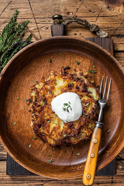 Tortitas de patata asada o buñuelos con hierbas en una placa de madera