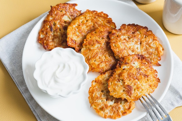 Tortitas de patata o latkes o draniki con crema agria Comida ucraniana Un plato de patata rallada de Deruny o Draniki