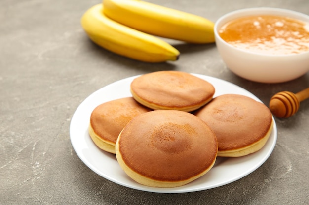 Tortitas de plátano caseras con mantequilla en plato sobre fondo gris Espacio para texto